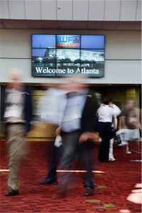 Convention attendees move through the Georgia World Congress Center in Atlanta with a 3x3 videowall made up of 46-inch monitors in the background.