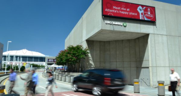 Convention attendees move through the Georgia World Congress Center in Atlanta with a 3x3 videowall made up of 46-inch monitors in the background.