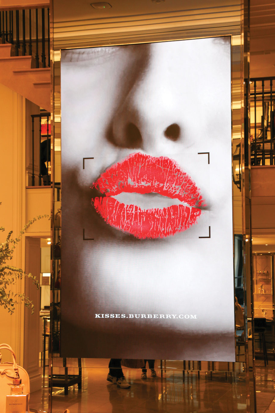 Video displays are nestled in with products in Burberry Coach stores.