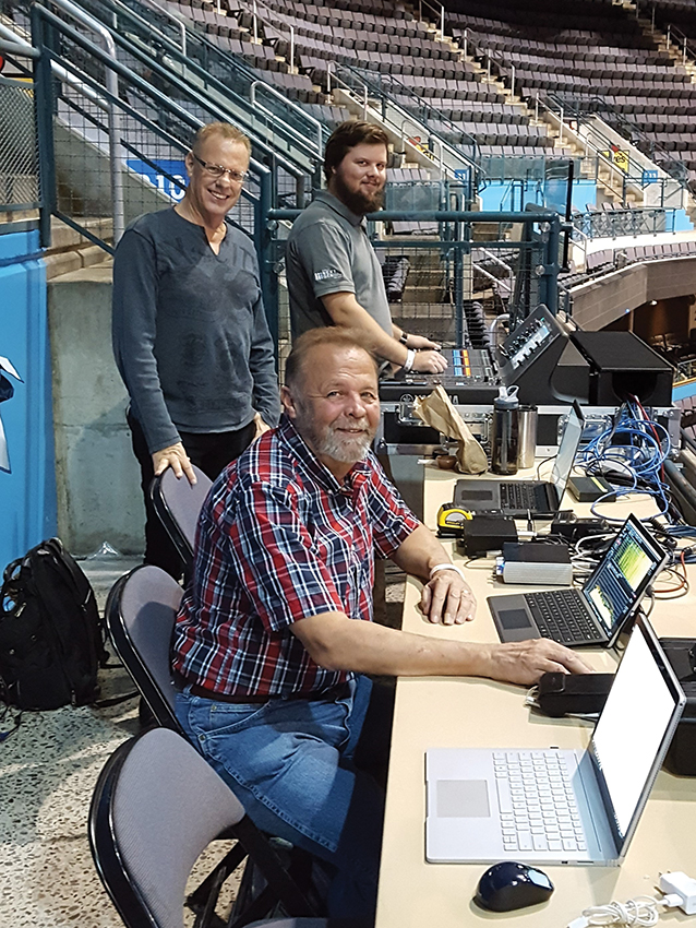 The commissioning team for the new sound system includes Marsh/PMK’s David Marsh (left, rear), Ford AV’s Brent Kuchero (right, rear) and Marsh/PMK’s Jerrold Stevens. The new digital mixing console in its road case can be seen in the background (being operated by Kuchero). This was specified so the sound could be mixed from out in the arena rather than in an enclosed booth.
