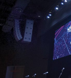 Line arrays with flown subs are hung to the left and right of the LED screen.