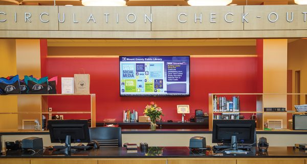 The library’s captive audience is never far from digital signage, such as this example at the circulation desk.
