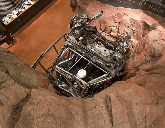 The Crash Pit exhibit lets visitors watch a replay of an iconic crash, sourced from one of four DVD players, on a 32-inch flatpanel monitor nestled just about inside the twisted wreck, while sounds simulating the crash and other audio elements play through a loudspeaker also hidden inside the wreck.