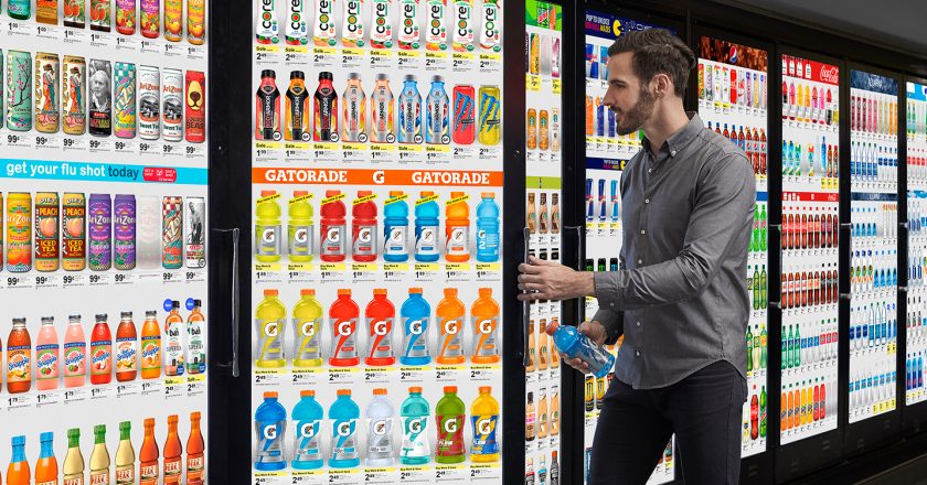 man grabbing beverage from refrigerator with a digital screen