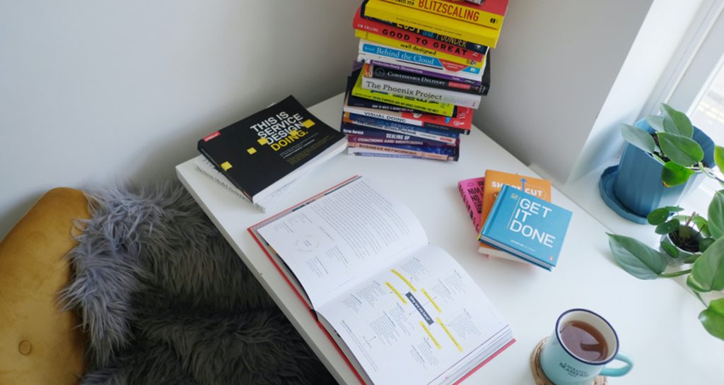 desk with stacks of books and a cup of tea