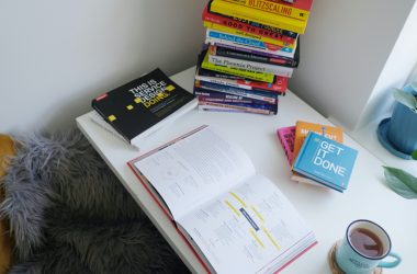 desk with stacks of books and a cup of tea