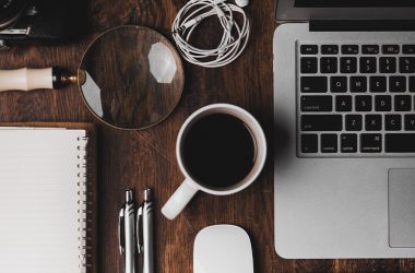 desk with notebook, pens, laptop, and coffee for house of worship management