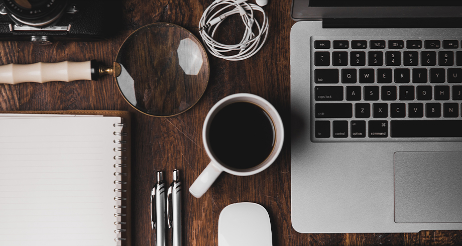 desk with notebook, pens, laptop, and coffee for house of worship management